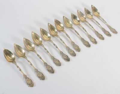 six cuillères en argent sont alignées sur une surface blanche