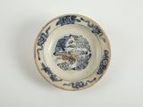 une vieille assiette bleue et blanche sur laquelle est représenté un oiseau