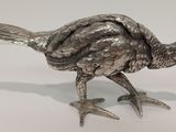 un oiseau argenté posé sur une surface blanche