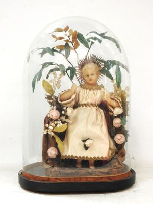 une figurine représentant une petite fille assise sur une chaise sous une cloche en verre