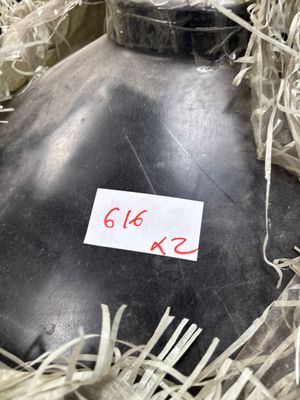 a black bottle with a sticker on it sitting in a pile of shredded paper