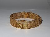 bracelet doré orné d'un motif en filigrane sur un fond blanc