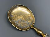 une cuillère en or ornée d'un motif, posée sur une table