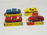 four toy cars are lined up in a row on a white surface