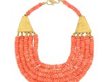 un collier composé de perles de corail et de touches dorées sur fond blanc