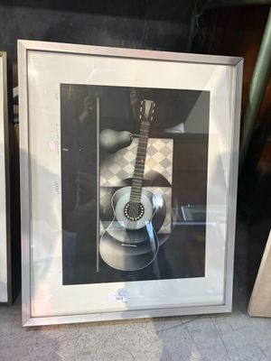 une photo d'une guitare dans un cadre, posée sur le rebord d'une fenêtre