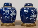 two blue vases with white flowers on them sitting on a table