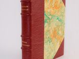an old book with a red cover sitting on top of a white surface