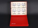 a red box with six wine glasses in it on a black surface