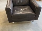 black leather chair in a warehouse with other furniture in the background