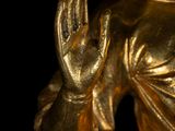 a gold statue of a woman holding her hands up
