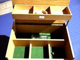 une petite boîte en bois compartimentée, posée sur un fond bleu