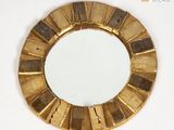 a round mirror with a gold frame on a white surface