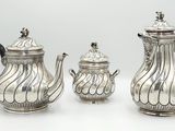 three pieces of silver tea and coffee set on a white surface