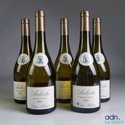 quatre bouteilles de vin blanc sont alignées sur une table