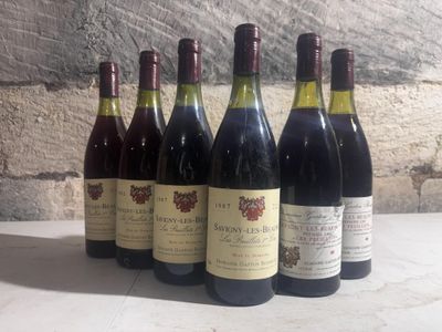 several bottles of wine are lined up on a table in front of a brick wall