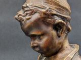 bronze statue of a boy reading a book on a black background