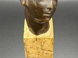 a close up of a sculpture of a woman ' s head on a wooden block