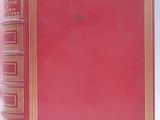 an old red book sitting on top of a table next to a white wall