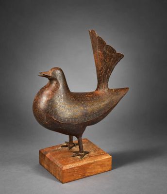 une sculpture en bronze représentant un oiseau, posée sur un socle en bois