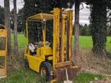 two yellow forklifts parked next to each other in a field