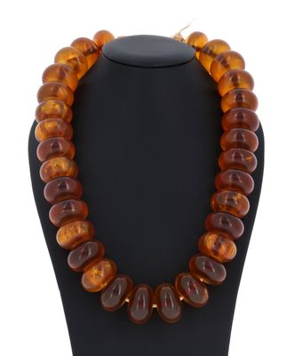 un collier composé de perles d'ambre de la Baltique, présenté sur un mannequin noir