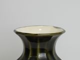a green vase sitting on a table with a white wall in the background