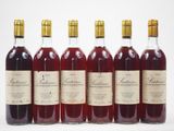 six bouteilles de vin sont alignées sur une surface blanche