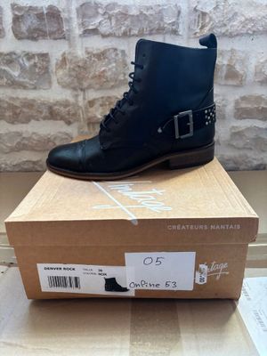 black leather ankle boots with buckles on top of a cardboard box