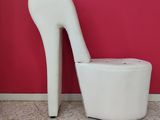 a white chair with a high heel on it in front of a red wall