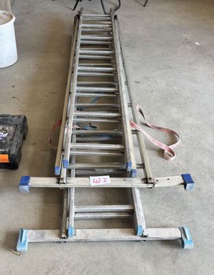 une échelle posée par terre à côté d'une boîte à outils