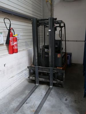 un chariot élévateur dans un garage où un extincteur est accroché au mur