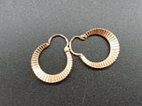a close up of a pair of gold earrings on a black surface