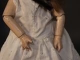 a close up of a doll wearing a white dress and a black tie
