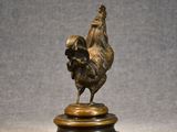 an image of a bronze statue of a rooster on a wooden base