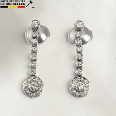 deux paires de boucles d'oreilles en diamant posées sur une surface blanche