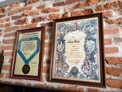 two framed plaques on a brick wall above a plaque