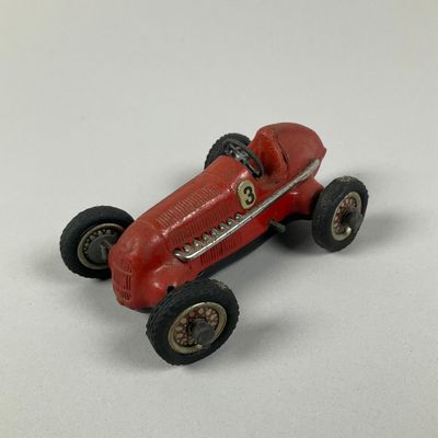 a red toy car that is sitting on a white surface