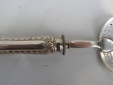 a silver spoon with a handle on a white surface