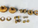 a lot of gold rings and earrings on a white surface