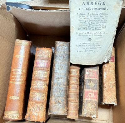 many old books in a cardboard box on the floor