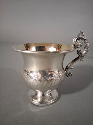 une coupe ancienne en argent avec une anse, posée sur une table