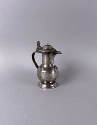 silver plated coffee pot with lid on a plain surface