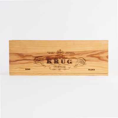 La boîte en bois contient une bouteille de vin et une autre boîte en bois sur laquelle est inscrit le mot « Krug ».