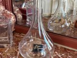 a glass vase sitting on a table next to bottles of perfume