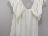 white blouse hanging on a hanger in a room with a white wall