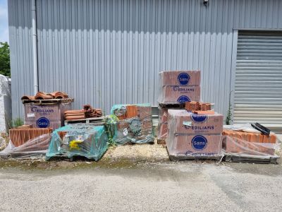 Plusieurs caisses de briques sont empilées les unes sur les autres devant un bâtiment