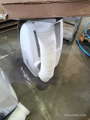 a white air conditioner sitting on the floor next to a box