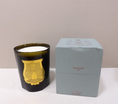 La bougie se trouve à côté de la boîte, sur la table.