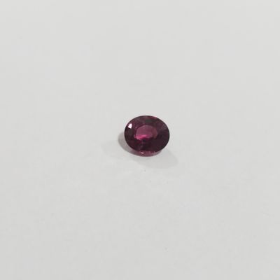 a close up view of a red garnet stone on a white surface